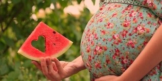 watermelon slice in the hands of a pregnant woman